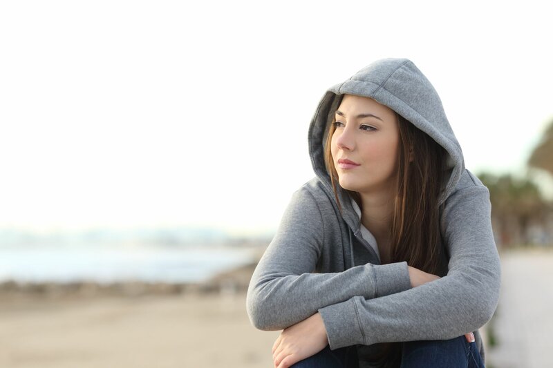 Jonge vrouw kijkt uit over het strand
