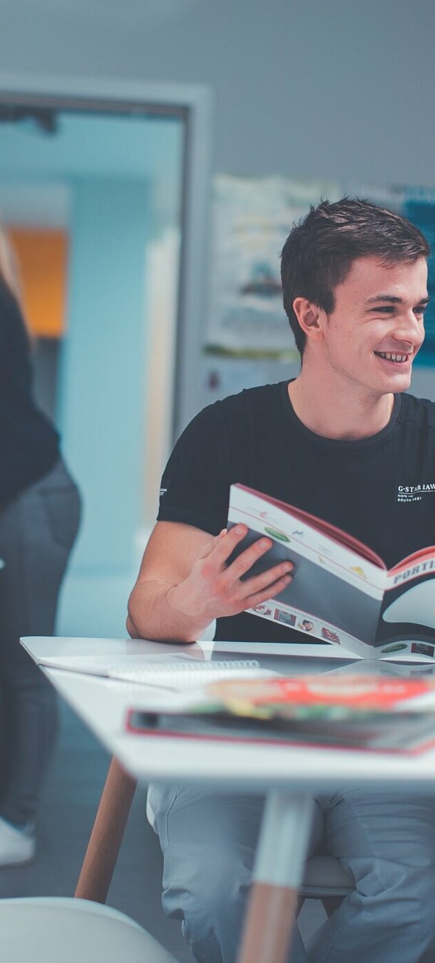 Twee studenten aan een tafel met een tijdschrift